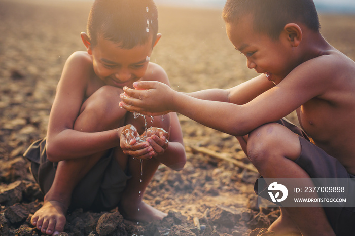 Asian local boys holding water with his hand at dry cracked land, Climate change, Environment conservation and stop global warming concept