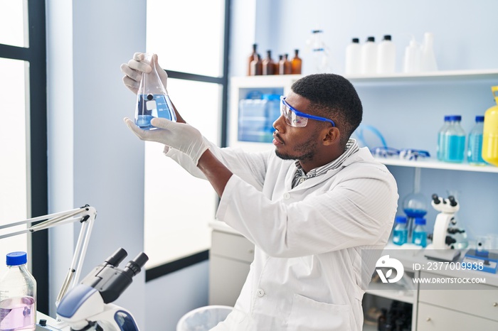 Young african american man wearing scientist uniform holding test tube at laboratory