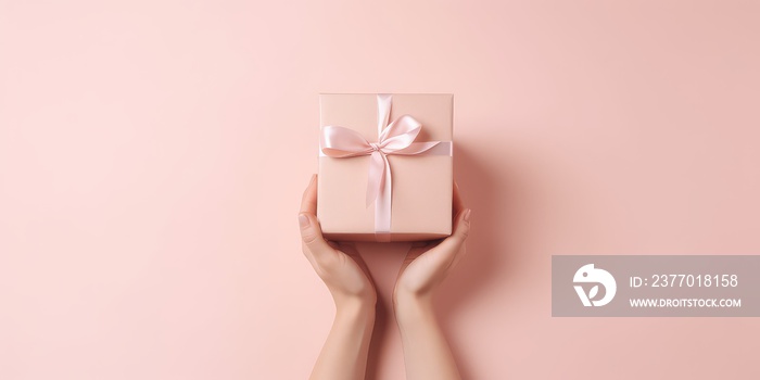 christmas background with hands holding present box on a pink background.
