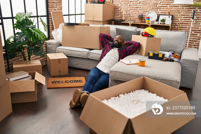 Young african american man relaxed with hands on head sitting on floor at new home