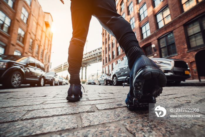 Man running at New York City street at sunset time. Men’s feet with sport sneakers outdoors.