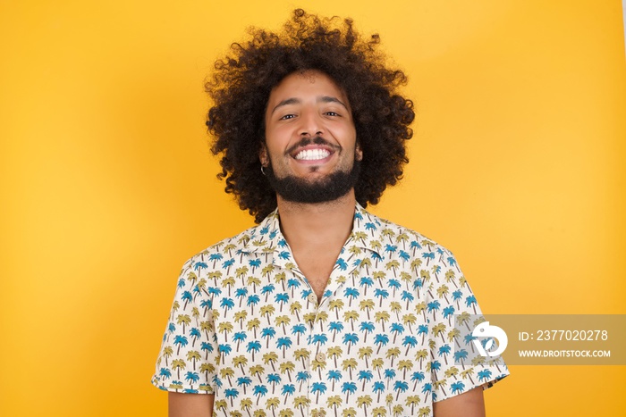 Young man with afro hair over wearing hawaiian shirt standing over yellow background with a happy and cool smile on face. Lucky person.