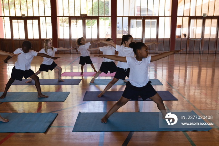 Schoolkids doing yoga on a yoga mat in school