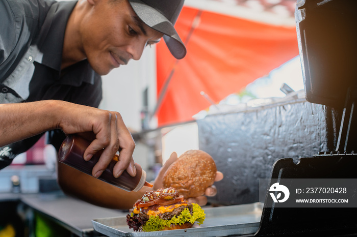 Cook in a food truck or burger joint finishing a cheeseburger