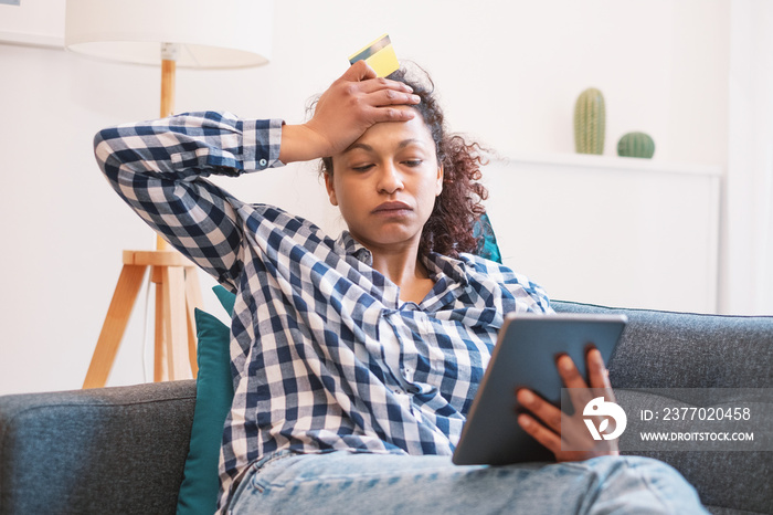 Sad black woman concerned holding credit card for home shopping