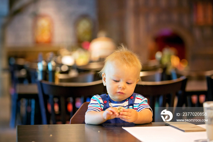 Little boy, child, enjoying breakfast in hotel restaurant