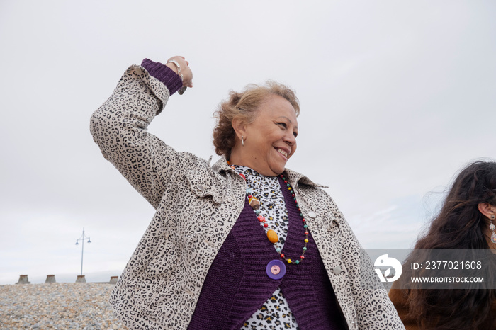 Smiling senior woman skimming stones on beach