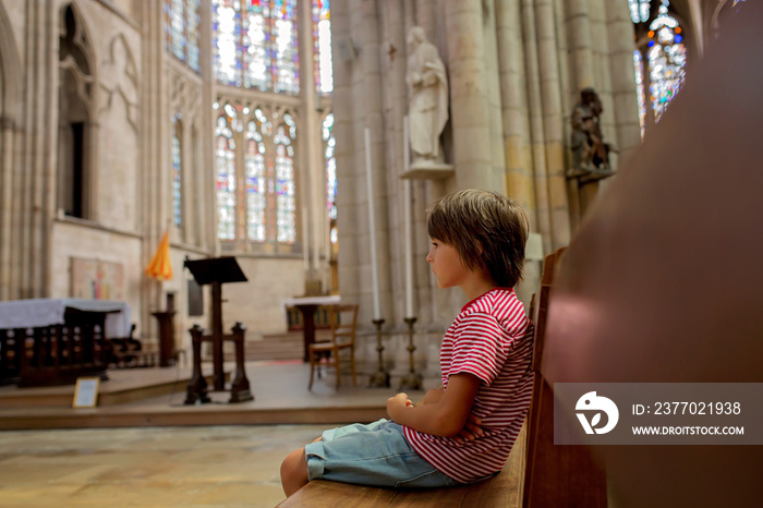 Little boy prays and puts a candle in Orthodox Church.