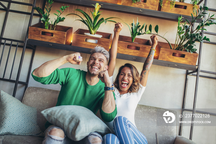 Modern couple looking excited and happy after their favorite football team scored a touchdown