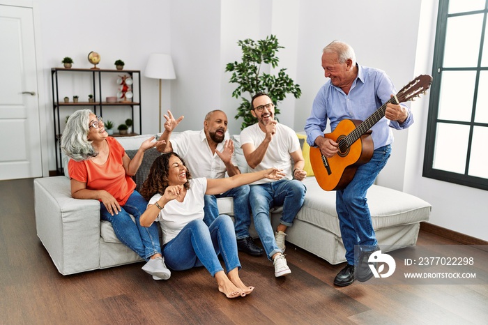 Group of middle age friends having party playing classical guitar sitting on the sofa at home.