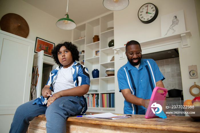 Father helping his son with homework in the kitchen