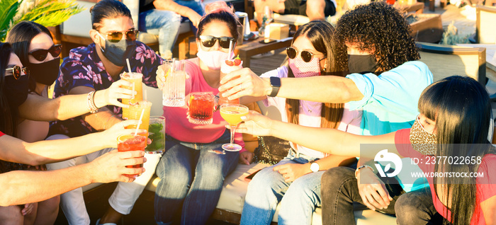 Friends drinking cocktail at bar with face masks