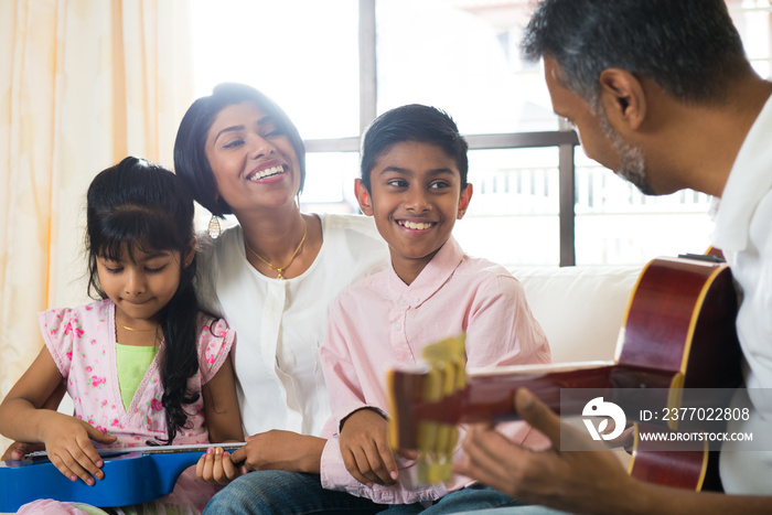 indian family enjoying quality time playing guitar at house