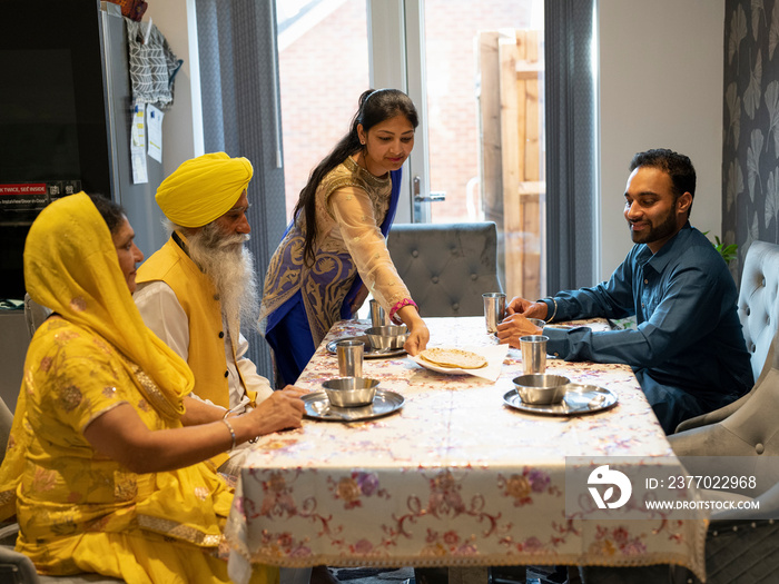 Family in traditional clothing eating meal at home