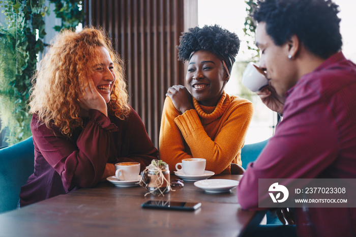 Two ladies drinking coffee and talking with a male friend. They were touched by his romantic story.