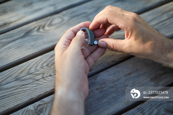 Closeup senior man changing button battery of electronic hearing aid in his hand