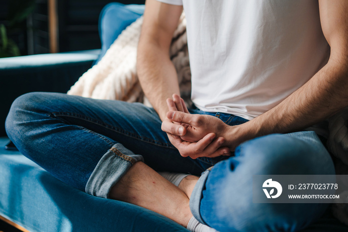 Close-up view of a boy’s hands standing together with his legs in a yoga position. Cozy apartment. Breathing exercise.