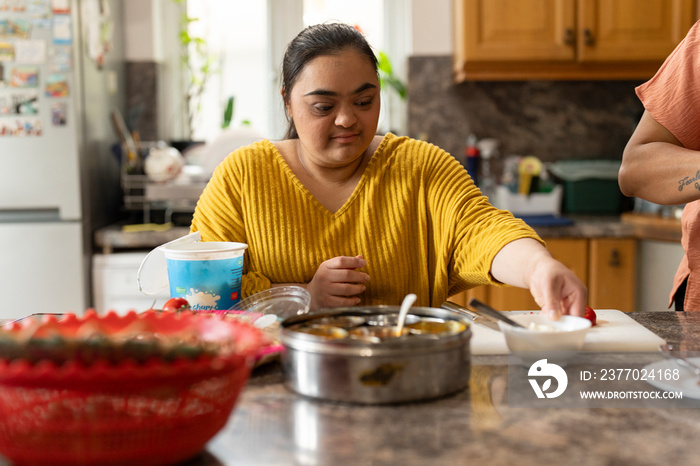 Young woman with down syndrome preparing food in kitchen