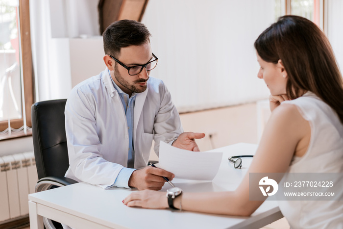 Male doctor with female patient reading reports on paper