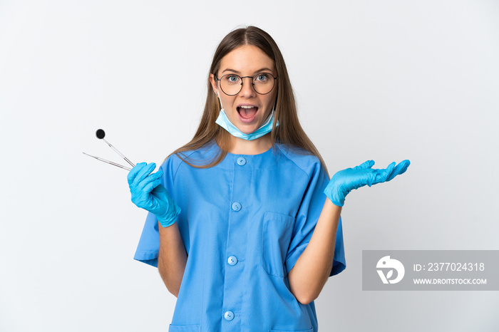 Lithuanian woman dentist holding tools over isolated background with shocked facial expression