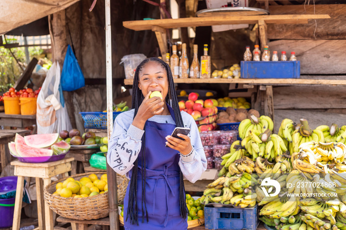 young black African businesswoman in a local market browsing online using smartphone checking reading news online