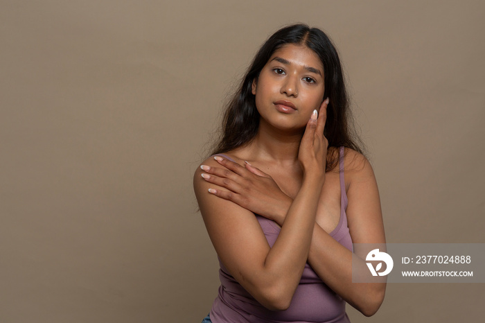 Studio portrait of pensive woman in purple top touching face