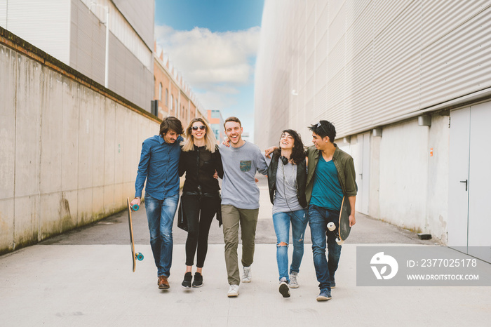 Group of friends skaters walking outdoors having fun hugging and enjoying time together