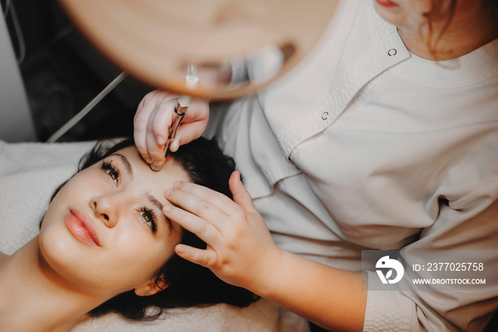 Upper view lovely female face leaning on a spa bed with eyes opened doing noninvasive microdermabrasion on her face by a cosmetologist in a spa center.