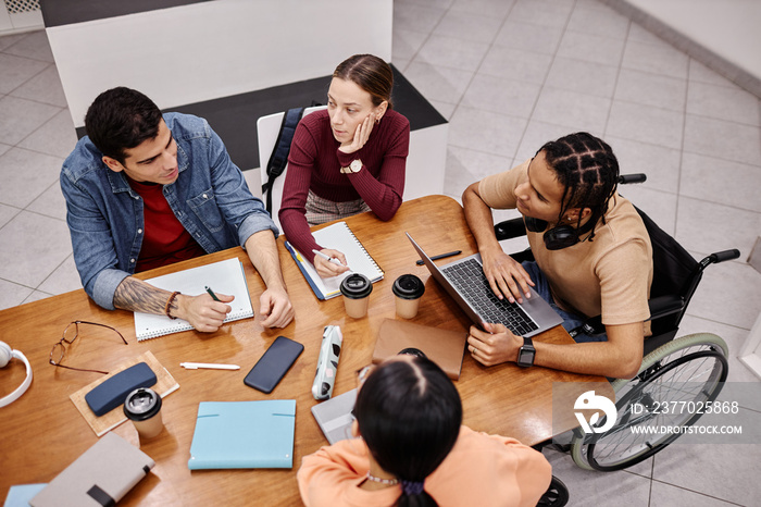 Diverse group of young people studying together in college library