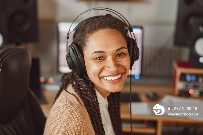 Young African composer musician with headphones in recording studio smiling beautiful toothy smile while looking at camera