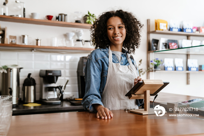 Young black female barista standing by paying terminal in cafe