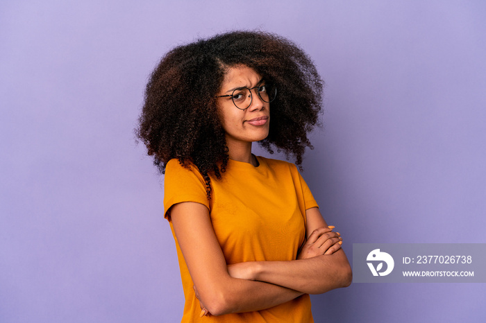 Young african american curly woman isolated on purple background suspicious, uncertain, examining you.