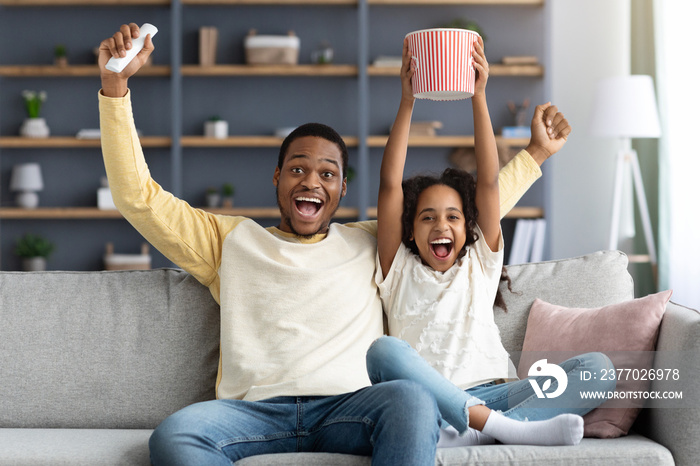 Emotional black family father and daughter watching football game together