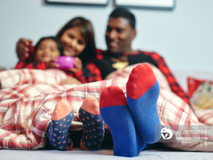 Feet of parents sitting in bed with son