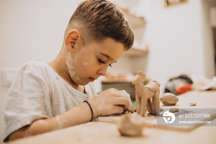 Cute boy forming toys from clay