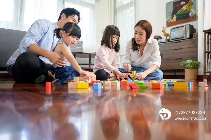 Asian family with children playing and building tower of colorful wooden toy blocks in living room at home, Educational game.