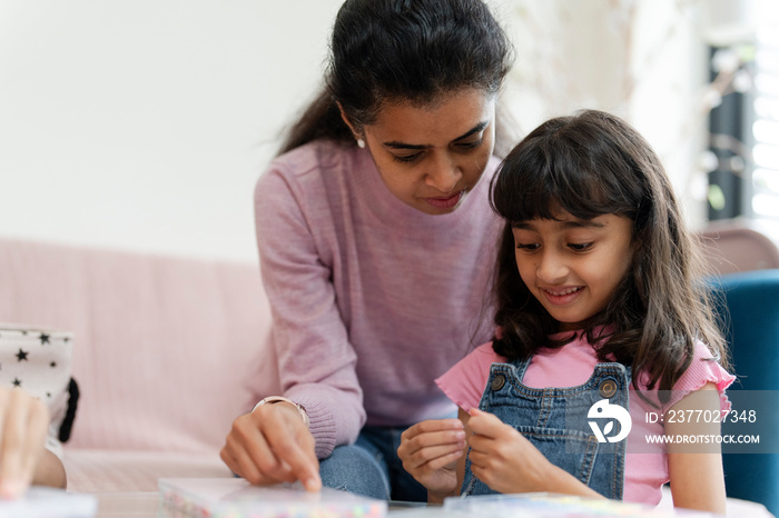 Mother with daughter playing with beads in living room