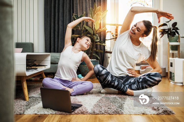 Beautiful young mother practicing fitness exercising and yoga together with her adorable little son. They are enjoying, playing and smiling.