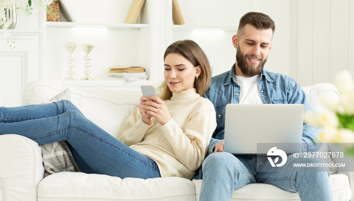 Couple at home. Man with laptop, woman with phone