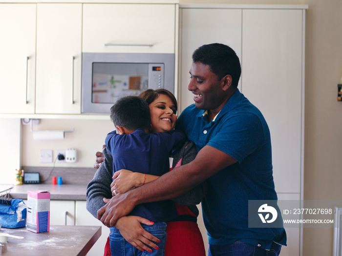 Parents and son hugging in kitchen