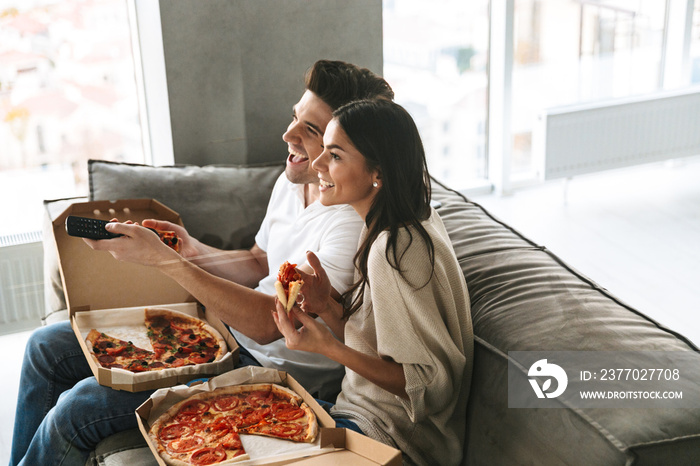 Cheerful young couple sitting on a couch at home