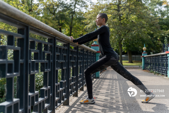 Athletic woman stretching legs on footbridge in park