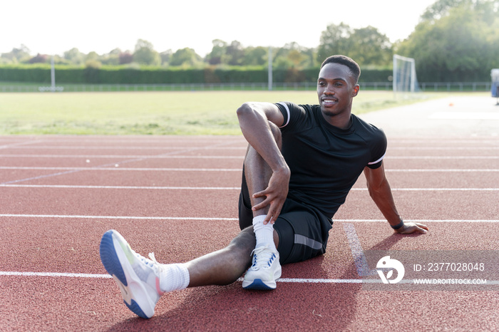 Athlete stretching legs before training at sports track