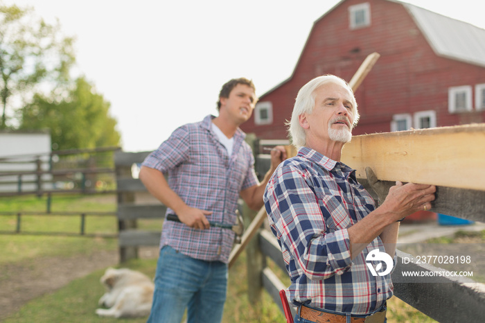 Father and son repairing fence on rural property.