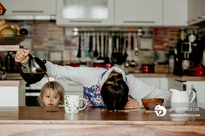 Tired mother, trying to pour coffee in the morning. Woman lying on kitchen table after sleepless night