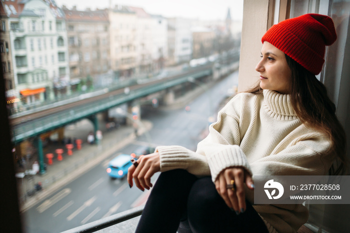 Young woman sitting close to window and looking out