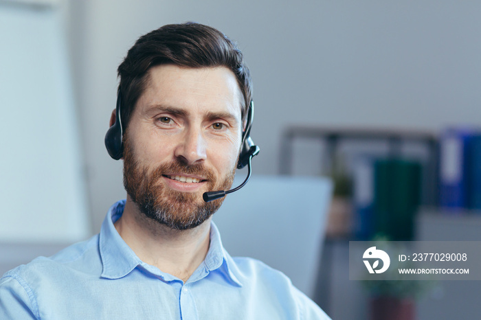 Close-up portrait of a businessman with a headset for a video call, a man looking at the camera smiling, a call center operator