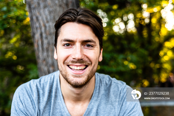 Close-up of a handsome young man model looks straight in front of the camera on a sunset