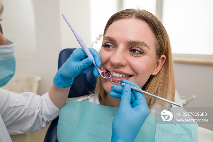 Close-up of a dentist in a mask and a patient, a dentist treating a cheerful young blonde patient smiling.