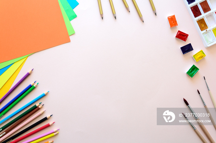 School stationery on pink paper. Colored pencils, pens, pains, paper, brushes for school and student education. Back to school. Copy space. Top view. Flat lay